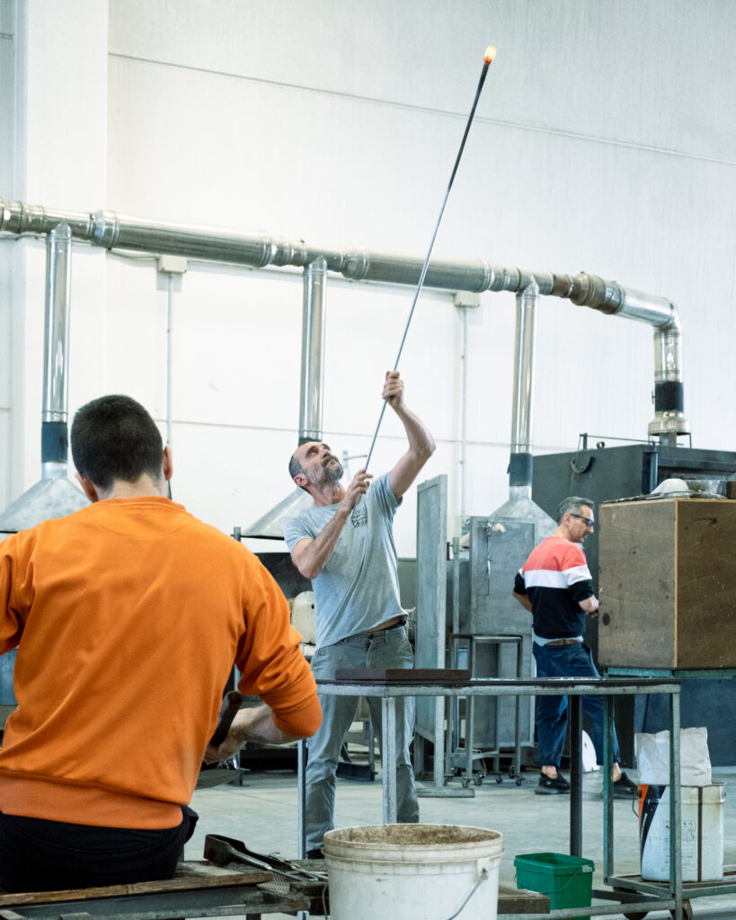 Maestro vetraio al lavoro in una fornace Murano durante la lavorazione artigianale del vetro incandescente
